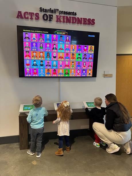Children look up to see their act of kindness appear on a huge screen.